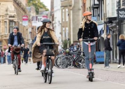 Varias personas paseando con bicis y patinetes de Voi.