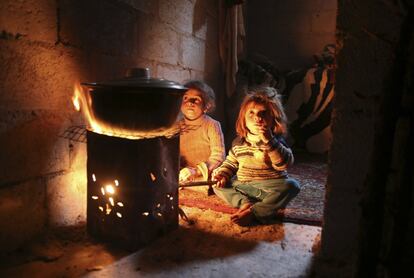 Unos niños se calientan alrededor del fuego en Ghouta cerca de Damasco (Siria). 