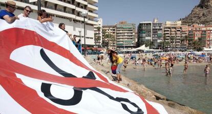 La pancarta de los sindicatos contra los recortes fue desplegada en la playa del Postiguet de Alicante.