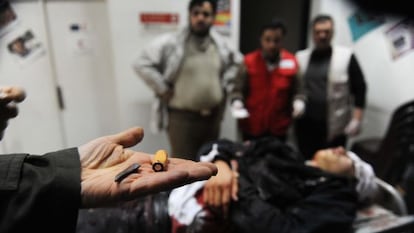 Un hombre muestra proyectiles ante un cadáver en la ciudad de Idlib.