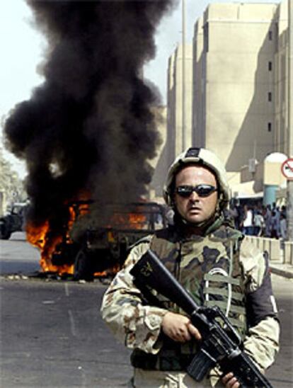 Un policía militar vigila junto a un vehículo blindado atacado en Bagdad.