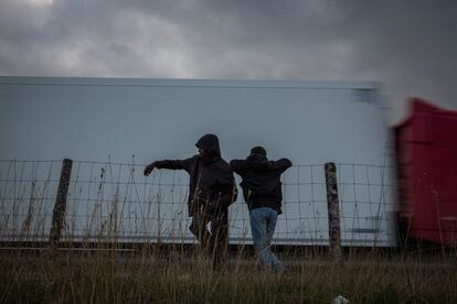 Dos hombres esperan a un lado de la carretera que conduce a la terminal del Eurotúnel en Coquelles, Calais (Francia)