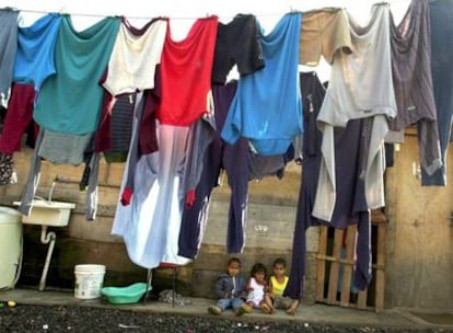 Tres niños, ante la puerta de la chabola en que viven, en una favela de São Paulo.