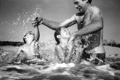 An adult plays with two children at a beach in Royan, France, in a photograph from 1982.