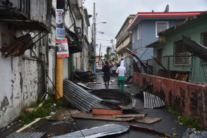 El paso del huracán María por Puerto Rico este miércoles ha dejado sin luz a la totalidad de sus 3,5 millones de habitantes. En la imagen, dos hombres caminan entre los destrozos provocados por el paso del huracán en San Juan, la capital de Puerto Rico.