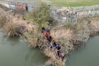 A group of migrants attempt to go through a wire fence on the banks of the Rio Grande river as members of U.S. National Guards stand guard on the other side of the fence in Eagle Pass, Texas, U.S., February 27, 2024.