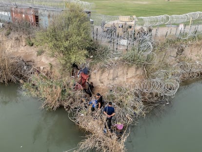 A group of migrants attempt to go through a wire fence on the banks of the Rio Grande river as members of U.S. National Guards stand guard on the other side of the fence in Eagle Pass, Texas, U.S., February 27, 2024.