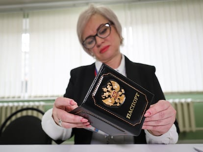 An election commission official inspects the passport of a person who came to vote at a polling station, during a presidential election in Makiivka, Russian-controlled Donetsk region, Ukraine, March 15, 2024.