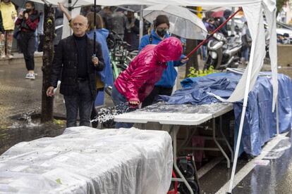 Libreros tratan de proteger los ejemplares de la lluvia, este sábado en Barcelona.