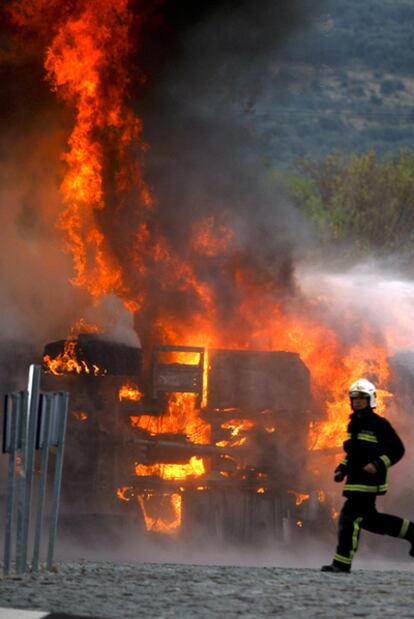 Un bombero corre ante el camión militar en llamas.