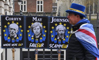 Un manifestante a favor de la estancia del Reino Unido en la Unión Europea camina junto a carteles que critican a Jeremy Corbyn (izquierda), Theresa May y Boris Johnson, en Londres.