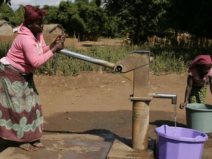 Una mujer, junto a su hija, saca agua de un pozo en su aldea en Malaui. 