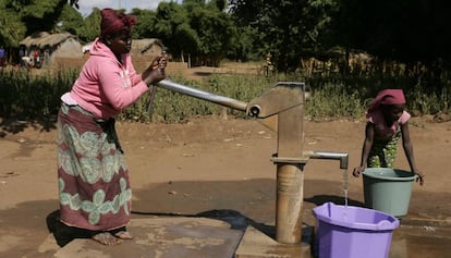 Una mujer, junto a su hija, saca agua de un pozo en su aldea en Malaui.