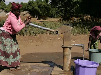 Una mujer, junto a su hija, saca agua de un pozo en su aldea en Malaui. 