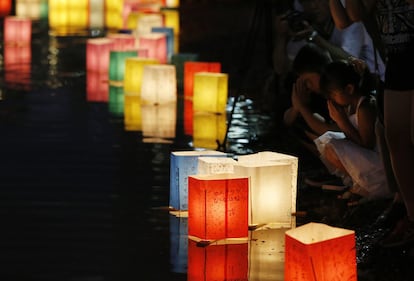 Niños rezan cerca de las linternas de papel depositadas en el río como parte de las actividades realizadas por el 71 aniversario conmemorativo de la bomba atómica de Hiroshimaen el Parque Memorial de la Paz de Hiroshima (Japón).