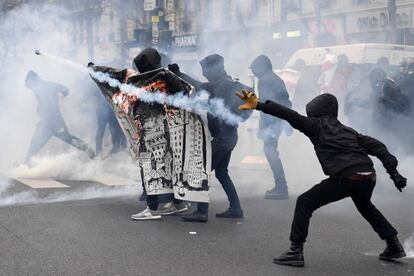 Unos manifestantes encapuchados lanzan botes de gas lacrimógeno durante sus enfrentamientos con la policía en una manifestación convocada en París contra la "brutalidad policial".