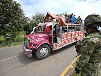 Indígenas colombianos a bordo de um ônibus ‘chiva’ passam diante de uma tropa militar nos arredores de Cali, na quarta-feira. Em vídeo, a participação dos indígenas nas manifestações.