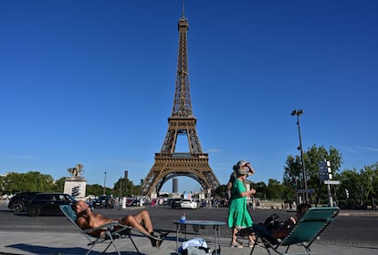 Dos parisinos sin vacaciones toman el sol frente a la Torre Eiffel.