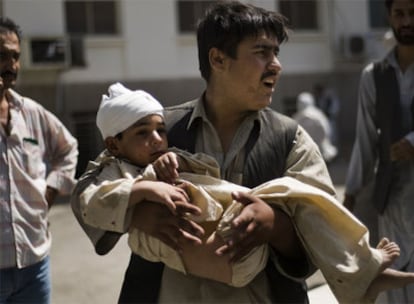 Un hombre lleva a un niño herido en el atentado suicida a las afueras de Kabul.