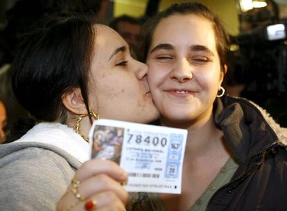 Tamara (d) y su hermana Jessica muestran un décimo del número 78.400, agraciado con el segundo premio de la Lotería de Navidad, junto a la administración del Centro Comercial "Carrefour-Los Ángeles", en Madrid, donde lo compraron.