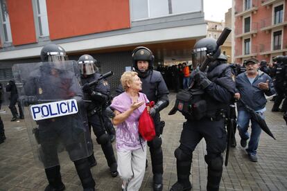 Antidisturbios (UIP) de la Policía Nacional disuaden a una mujer de acercarse al perímetro de seguridad en la Escola Mediterránea de la Barceloneta en Barcelona. Incidentes entre votantes y Guardia Civil y Policía Nacional en el día del referéndum ilegal independentista catalán del 1-O. Desafío independentista en Cataluña. 
