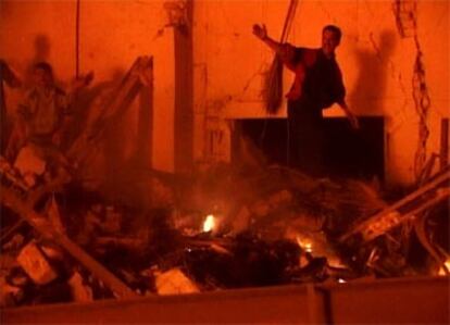 Una imagen de televisión muestra a varios iraquíes entre los escombros del hotel derruido.