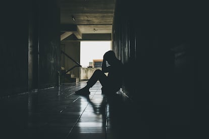 Un chico sentado en el suelo, con las manos en la cabeza, en actitud triste, en una foto de archivo.