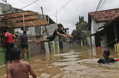 Jóvenes indonesios juegan en el agua que cubre las calles debido a una inundación en un barrio de Yakarta (Indonesia). 