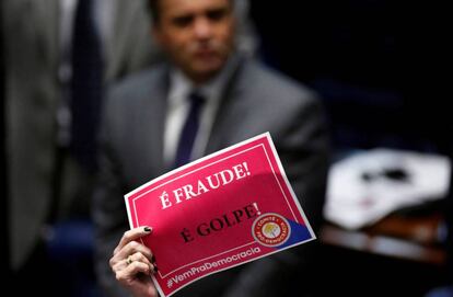 Senadora com um cartaz em protesto contra o impeachment; ao fundo, o senador Aécio Neves (PSDB).