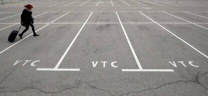 Una pasajera camina por el aparcamiento vacío de VTC en el aeropuerto de Barcelona.
