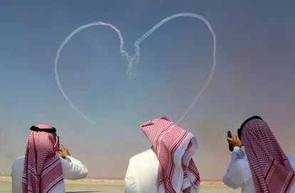 Tres espectadores fotografían un corazón hecho por las acrobacias de la patrulla Al Fursan de la fuerza aérea de Emiratos Árabes Unidos, en Dubai (EAU).