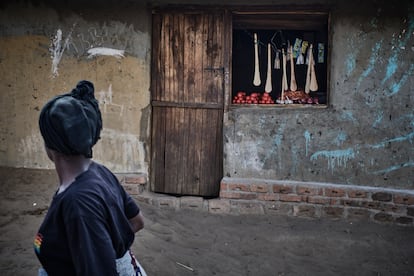 Una mujer pasa por delante de una tienda donde el propietario vende frutas, verduras y utensilios de cocina.