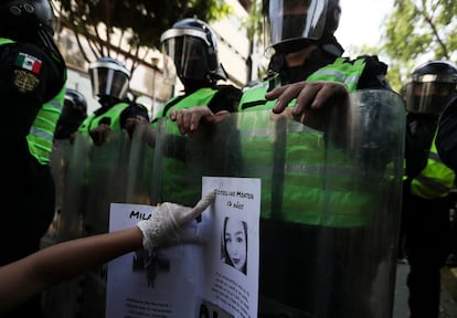 Una manifestante pega un volante de una víctima de violencia en el escudo antidisturbios de un policía en la Ciudad de México, en junio.