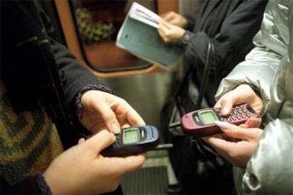 Unas estudiantes teclean en sus teléfonos móviles.