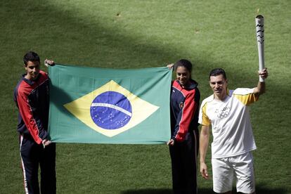 El exjugador brasileño de futbol Lucio sostiene la llama olímpica en el Estadio Nacional Brasilia (Brasil).