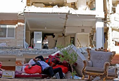 Un hombre iraní descansa junto a sus pertenencias rescatadas de un edificio dañado tras el terremoto en la localidad de Sarpol-e Zahab (Irán), cerca de la frontera con Iraq.