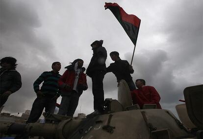 Un grupo de opositores a Gadafi se suben en Bengasi a uno de los tanques de las fuerzas de seguridad del régimen con la bandera de Libia antigua.