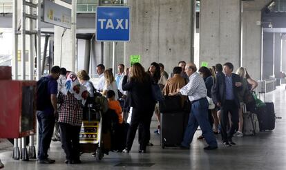 Una fila de viajeros espera junto a una parada de taxi en el aeropuerto de Barajas.