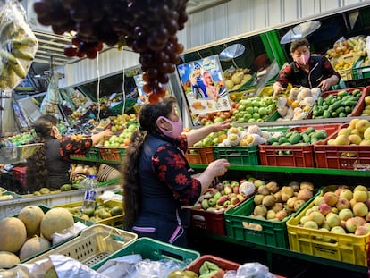 Una mujer con mascarilla acomoda frutas en su puesto del mercado en Corabastos el 27 de julio de 2020, en Bogotá, Colombia.