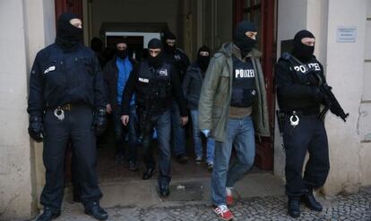 Agentes de polic&iacute;a alemanes abandonan un edificio de apartamentos en Berl&iacute;n durante la redada de este viernes.