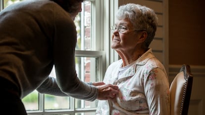A person buttons up an elderly woman's pajamas in an undated image