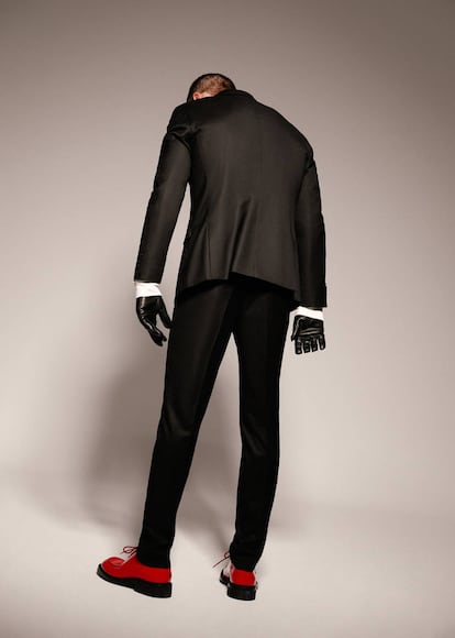Justin O’Shea posa para ICON con traje Mango Man, guantes Hermès y zapatos rojos Prada.