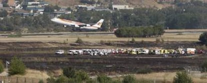 Un avión sobrevuela la zona del accidente, donde pueden verse los servicios de emergencia, tras despegar del aeropuerto de barajas ayer por la tarde, una vez el tráfico fue restablecido.