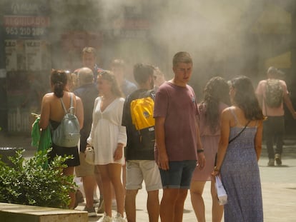 Varias personas se refugian del calor bajo unos vaporizadores de agua, este jueves en Valencia.