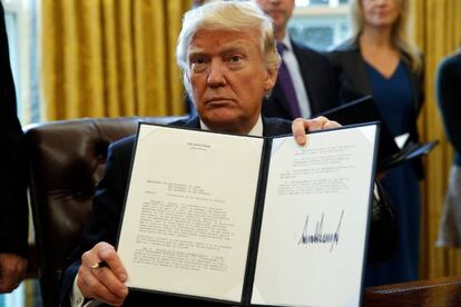 Donald Trump muestra su firma sobre una orden ejecutiva. 