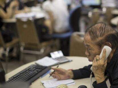 Un agente de bolsa habla por teléfono en una correduría en Hong Kong.