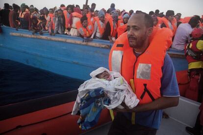Un hombre que lleva en brazos a su hijo de cinco días de edad, durante un momento de la operación de rescate frente a la costa de Libia.