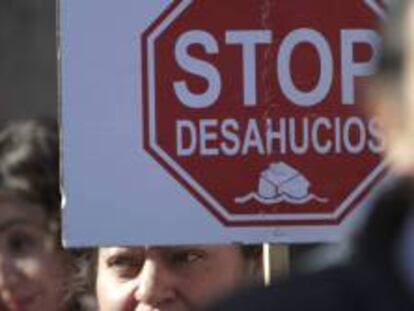 Una mujer sostiene un cartel contra los deshaucios en una manifestación.