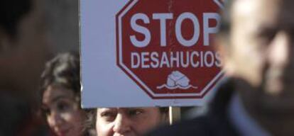 Una mujer sostiene un cartel contra los deshaucios en una manifestación.