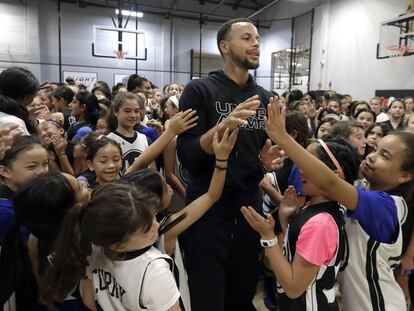 El jugador del Golden State Warriors Stephen Curry, junto a un grupo de niñas que practican baloncesto.